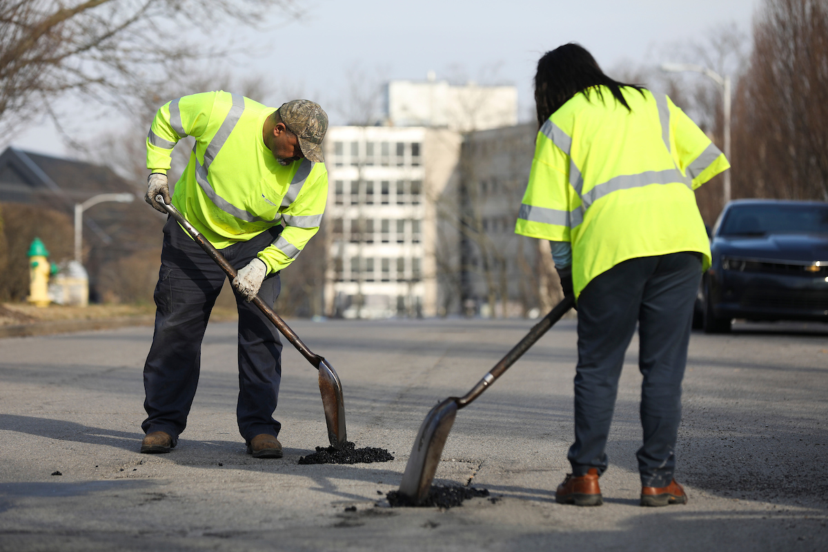 Chenice Ganns, public service worker senior, and Darrell Watkins, trades worker senior, both with Streets and Roads, fill potholes along Legion Drive and Man O’ War Place March 10, 2021.
