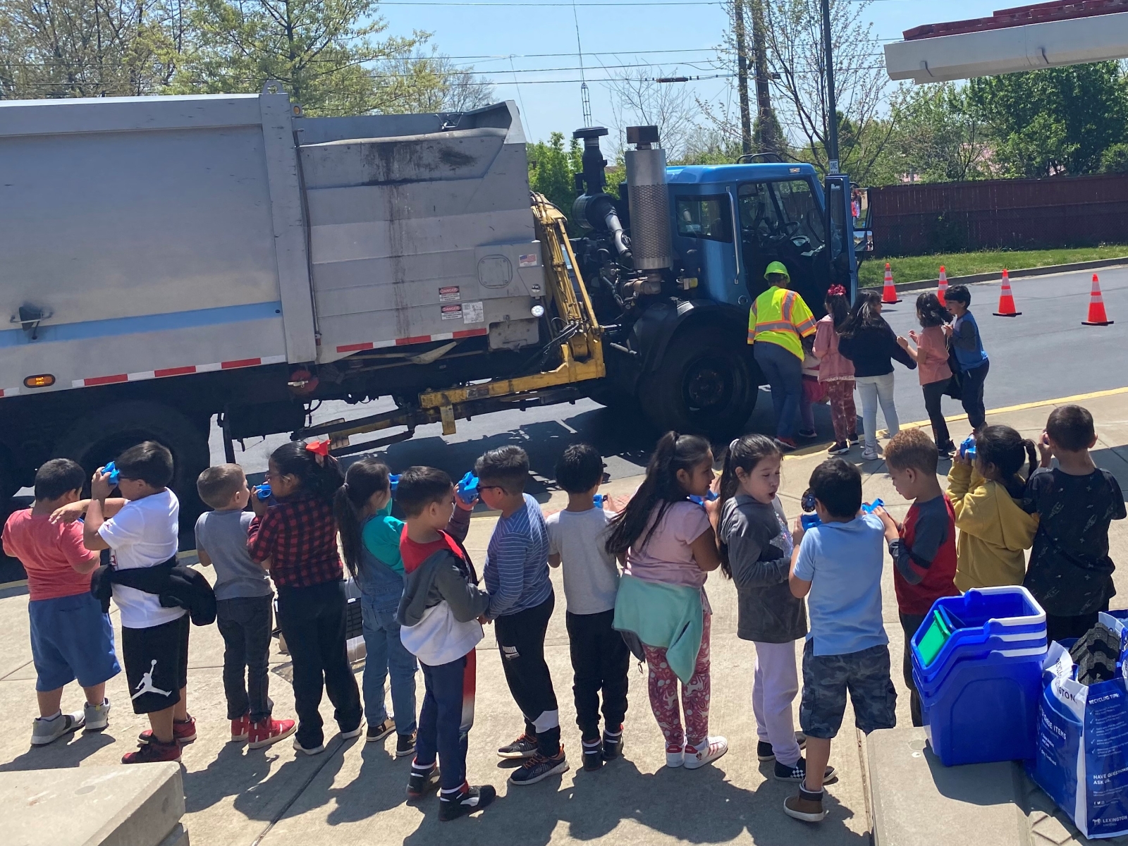 Group of elementary school children standing next to a recycling truck