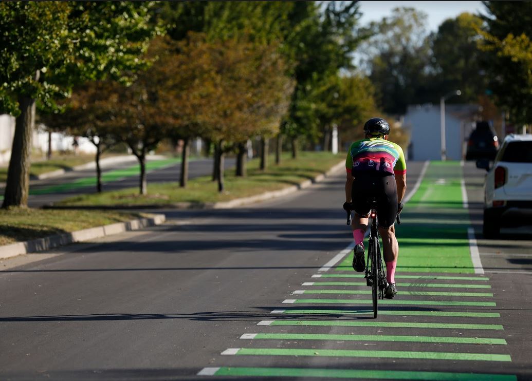 cyclist on green bike trail on street 