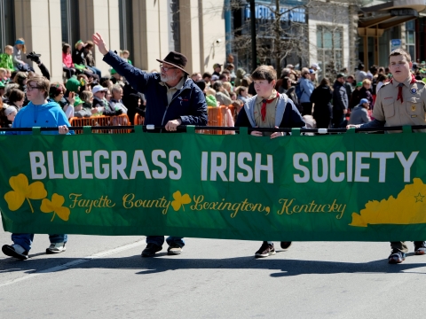 large banner being carried by people walking in a parade. Reads Bluegrass Irish Society. 