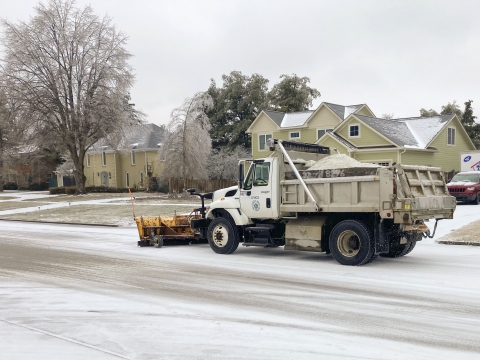 a salt truck release salt while driving down a snowy neighborhood street