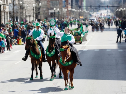 horses with riders dressed in green, walking in a parade down Main St. in Lexington