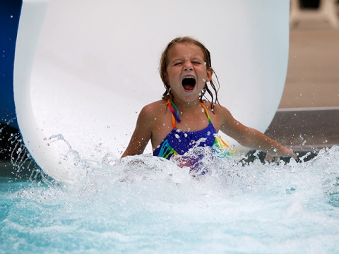 Young female going down a slide at a city pool.