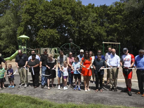large group, including Mayor Gorton, councilmembers and neighborhood residents cutting a ribbon in front of the new playground