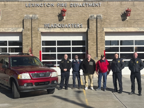 Members of the Lexington Fire Department and the Neon Volunteer Fire Department pose with a red SUV. 