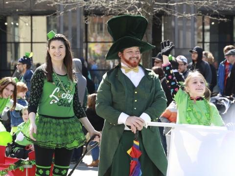 people dressed in green and other St. Patrick's attire walking down Main Street in Lexington for a parade