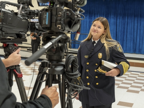 McKayla McKinney, wearing a firefighter dress uniform, is interviewed by the media. 
