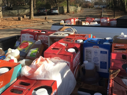 photo of boxes and jugs of cooking oil in the back of a pickup truck on a sunny day