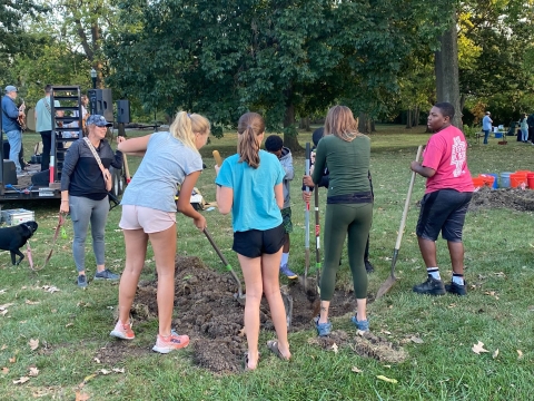 a photo of a group of college-aged students planting a tree 