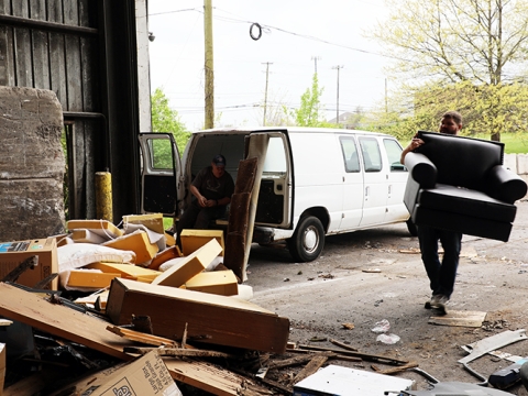 a man carrying an old chair into the transfer station warehouse area